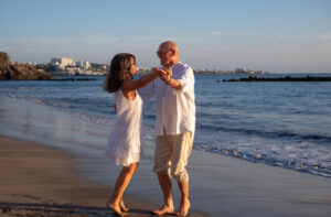 man and woman dancing on the beach at sunset